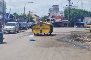 Bak Sampah BLHK Mengacam Maut PM, Kualasimpang - Bak sampah milik Badan Lingkungan Hidup dan Kebersihan (BLHK) Aceh Tamiang diletakKan di tengah badan jalan, tanpa memikirkan kesalamatan para pengguna jalan, baik pejalan kaki maupun pengendara bermotor yang melintasinya. Fenomena yang mengundang maut itu terekam pada, Senin (10/8) sekira Pukul 12.34 WIB, di tempat pembuangan sementara (TPS) sampah.  Bak tersebut terletak di kawasan persimpangan jalan Cut Nyak Dhien/Suparman, persis di depan ruko eks. stasiun Kereta Api Kota Kualasimpang. Foto: Syafruddin Buhfa.