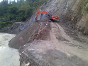 Alat berat terlihat membuang tanah ke dalam sungai saat proses pengerjaan jalan buka tutup di jalan lintas nasional Blangkejeren menuju Takengon.